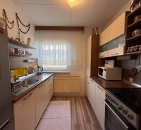 A kitchen in a family house with a wooden decor floor and white cabinets.