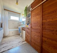 A bathroom with wooden cabinets and a bathtub in a family house.