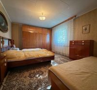 Bedroom in a family house with classic furniture, wooden decor flooring, curtains on the windows.