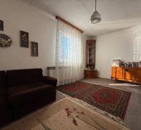 Living room in a family house with carpets, a sofa, and wooden furniture.