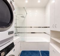 A bathroom in a 3-room apartment with a bathtub, a washing machine, and white furniture.