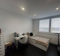 A room in a 3-room apartment with a bed, a table, and large windows.