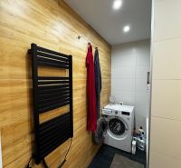 Bathroom with a washing machine, floor with wooden decor, towel dryer in a 3-room apartment.