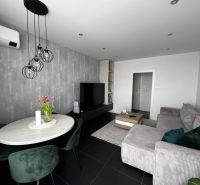 Living room in a three-room apartment with a comfortable sofa and a dining table.