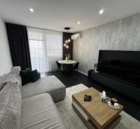 Living room of a three-room apartment with a corner sofa and a large television.