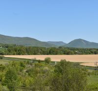 A picturesque landscape near Rožňava with fields, a road, and hills in the distance.