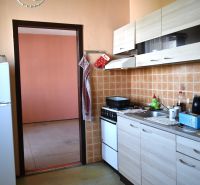 A kitchen in a 3-room apartment with tiled walls and a wooden decor floor.