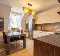 A kitchen in a 4-room apartment with a dining table, chandelier, and modern appliances.