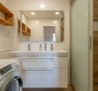Bathroom in a 4-room apartment, sink with mirror, washing machine, floor with wooden decor.