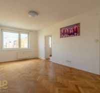 A spacious room with a large window, wooden decor flooring, and a painting in a 4-room apartment.