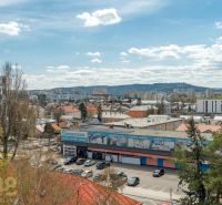 A view of Poprad from Partizánska Street shows 4-room apartments and a crowded parking lot.