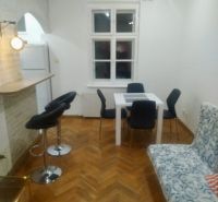 Living room in a two-room apartment with a wooden decor floor, dining table, and chairs.