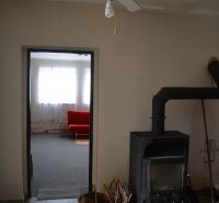 In the family house, there is a ceiling fan, a stove, and a red couch in the background.