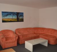 An orange sofa set and a painting in the living room of a family house.