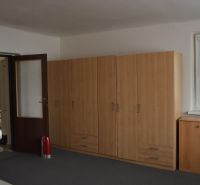 A room in a family house with brown cabinets, a window, and a door.