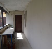 A hallway with white walls, cracks on the floor, a table, doors in a family house.
