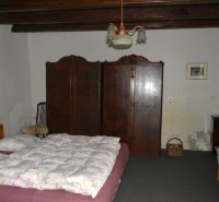 Bedroom in a family house with a bed, wardrobe, and chairs.
