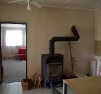 The interior of a family house with a fireplace, a fan, and a red sofa in the background.