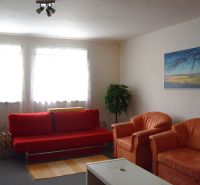 Living room of a family house with a red sofa and orange armchairs.