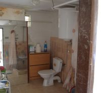 A bathroom in a family house with tiles, a shower, and a toilet.