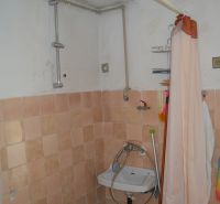 Bathroom with tiles and a curtain in a family house, simple sink.