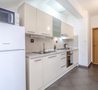 Bright kitchen in a holiday apartment with built-in appliances and tiling.