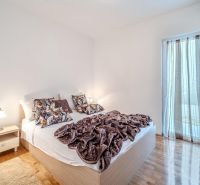 Bright bedroom with a bed and wood-decor flooring in a vacation apartment.
