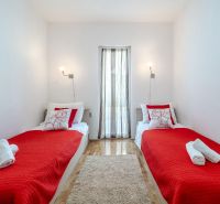 A recreational apartment with two beds, a red blanket, and a wooden-patterned floor.