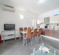 A bright kitchen with a dining table and a television in a holiday apartment.