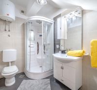 Bathroom in a holiday apartment with a modern shower and bright yellow towels.