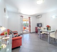 Bright living room with a sofa, dining table, and terrace in the Holiday Apartment.