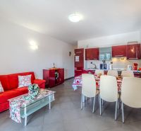 Recreational apartment with a red sofa and a kitchen with a dining area.