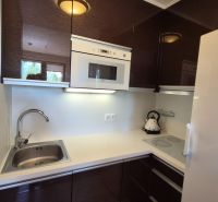A kitchen with white appliances and dark cabinets in a Holiday Apartment.