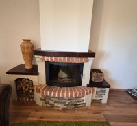 A fireplace in a recreational apartment with decorative stone and wood-patterned flooring.