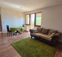 Living room with a sofa, dining table, shelf, and wooden decor flooring in a holiday apartment.