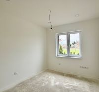 An empty room in a family house with white walls and a large window.