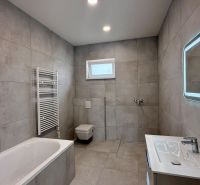 A family house bathroom with a bathtub, shower, and illuminated mirror.