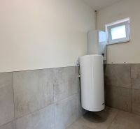 A bathroom in a family house with tiles on the walls and a boiler.