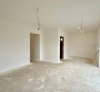 A spacious room with plaster walls and large windows in a family house.