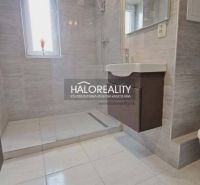 Bathroom in a 3-room apartment with a shower and a sink, light-colored tiles.