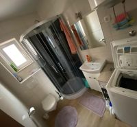 Bathroom in a holiday apartment with a washing machine, shower, and sink.