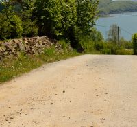 Paved road, trash can, and view of the lake in Nova Kelc, Recreational grounds.