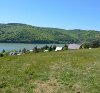 Recreational plots in Nová Kelča with a view of green hills and a water surface.