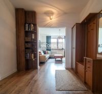 Entrance hall in a 3-room apartment, wooden decor flooring, bookshelf, bright living room.