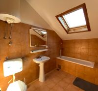 A bathroom in a holiday apartment with a bathtub and a skylight.