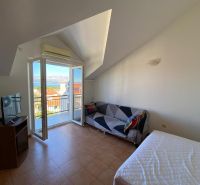 Room in a recreational apartment with a balcony and sea view, television, and sofa.