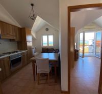 A kitchen of a holiday apartment with wooden cabinets and a sea view.