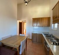 A kitchen in a holiday apartment with wooden cabinets and a dining table.
