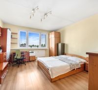A bedroom in a three-room apartment with a bed, a desk, and a floor with a wooden decor.