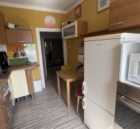 A kitchen in a 2-room apartment with yellow walls and a wooden decor floor.